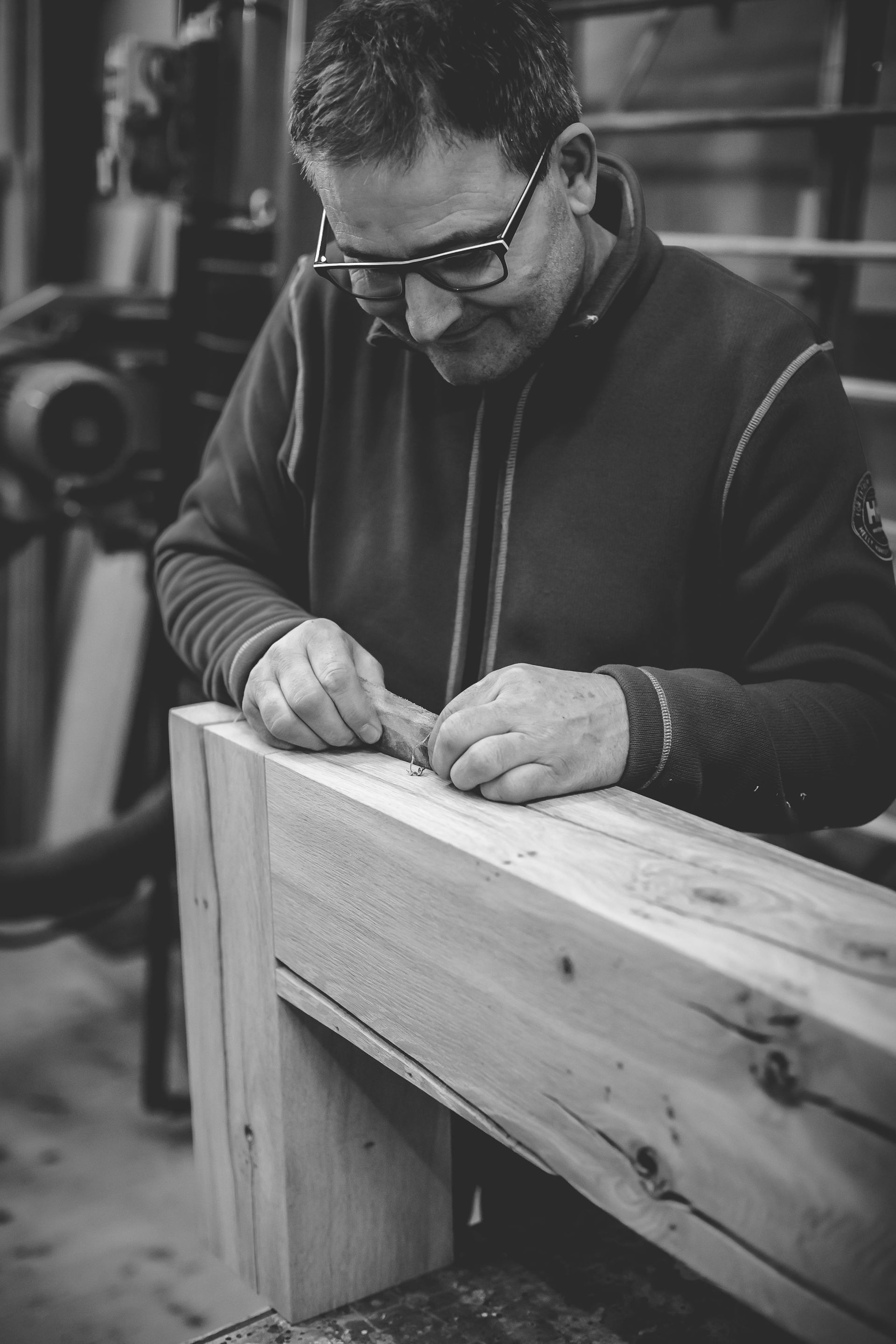 Auf einem Schwarzweissfoto arbeitet ein Mann an einem Stück Holz.