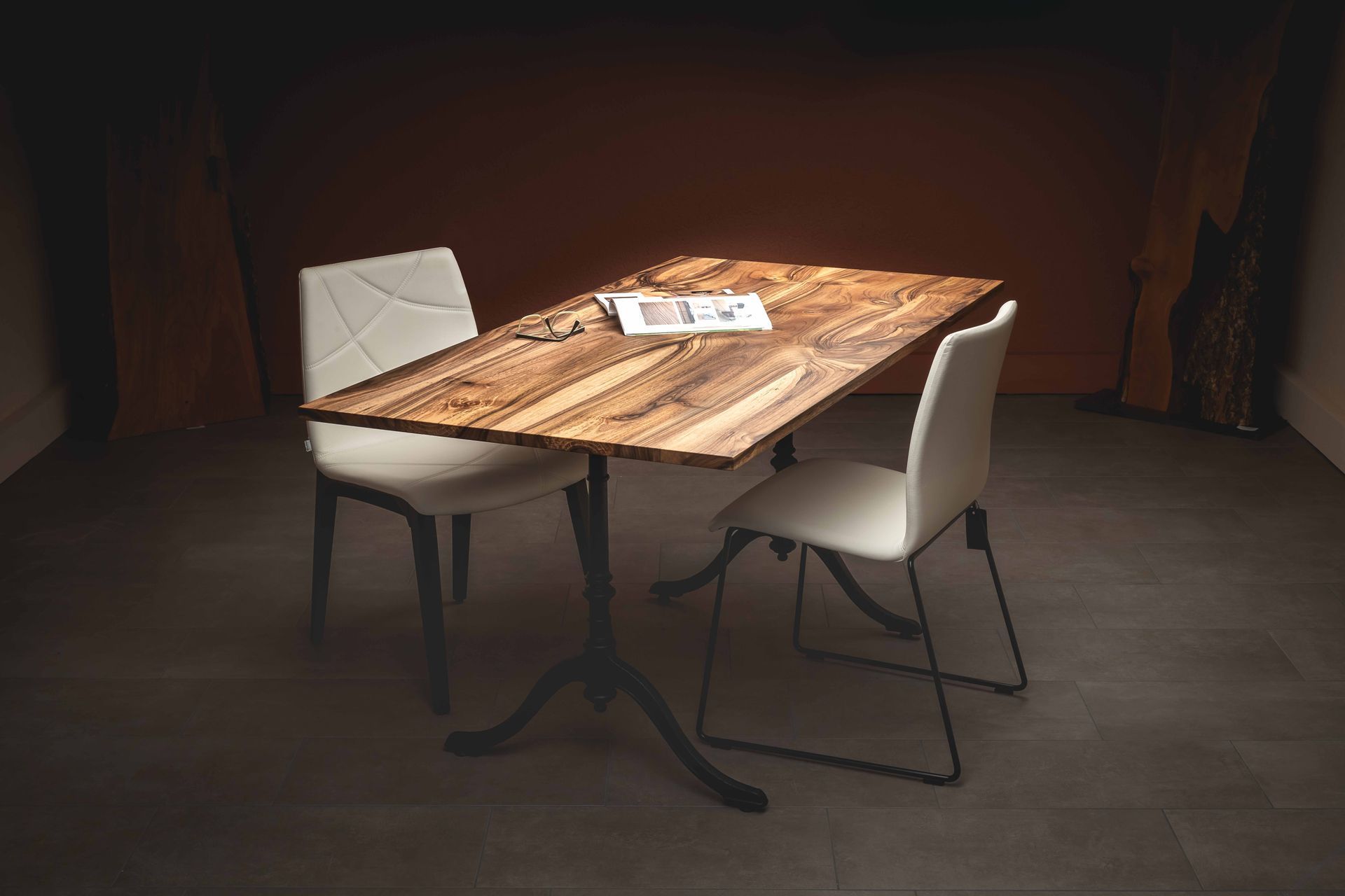 Ein Holztisch mit zwei weissen Stühlen in einem dunklen Raum.