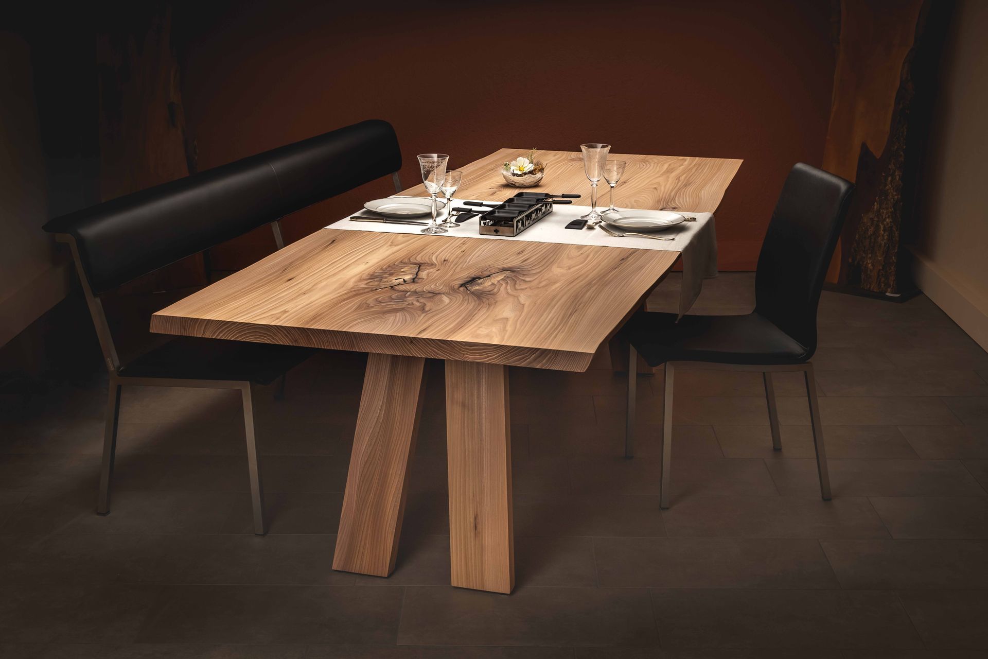 Ein Holztisch mit Tellern und Gläsern darauf in einem dunklen Raum.