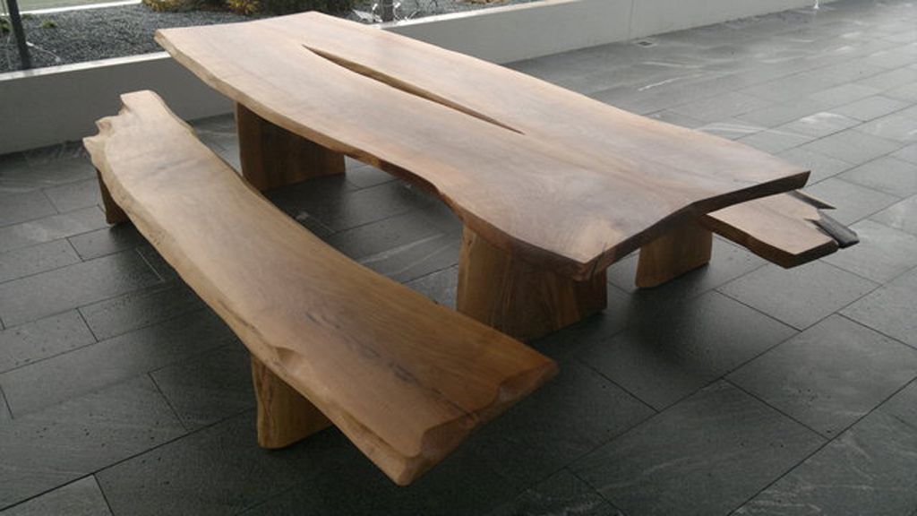 Ein hölzerner Picknicktisch mit zwei Bänken auf einem gefliesten Boden