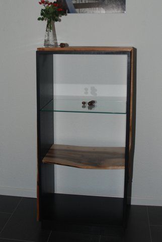 Ein Holzregal mit einer Glasablage und einer Blumenvase darauf.