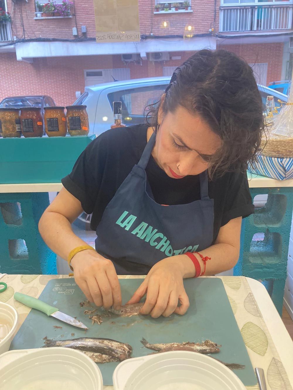 Una mujer con delantal está cortando un pescado en una mesa.