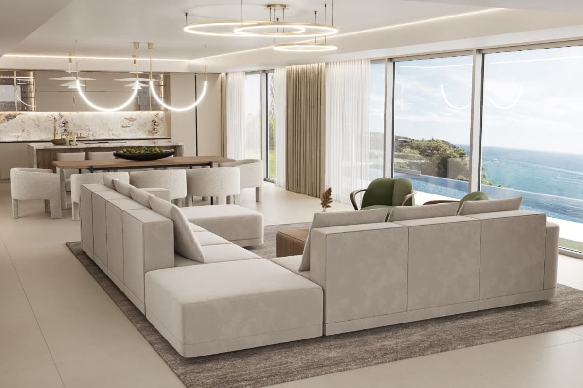 Una sala de estar con un gran sofá seccional y vista al océano.
