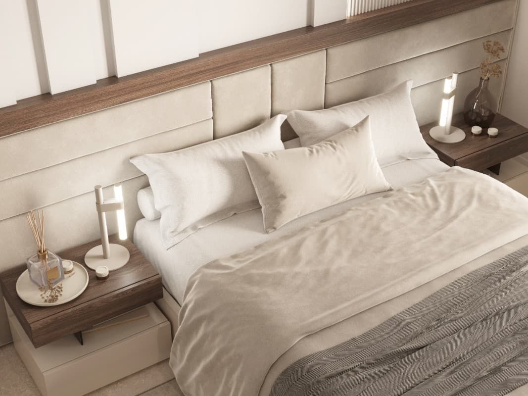 Una cama con sábanas blancas y almohadas en un dormitorio.