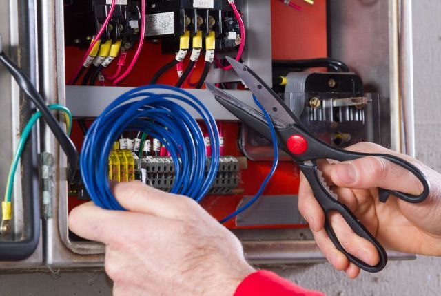 Una persona está cortando un cable azul con unas tijeras.