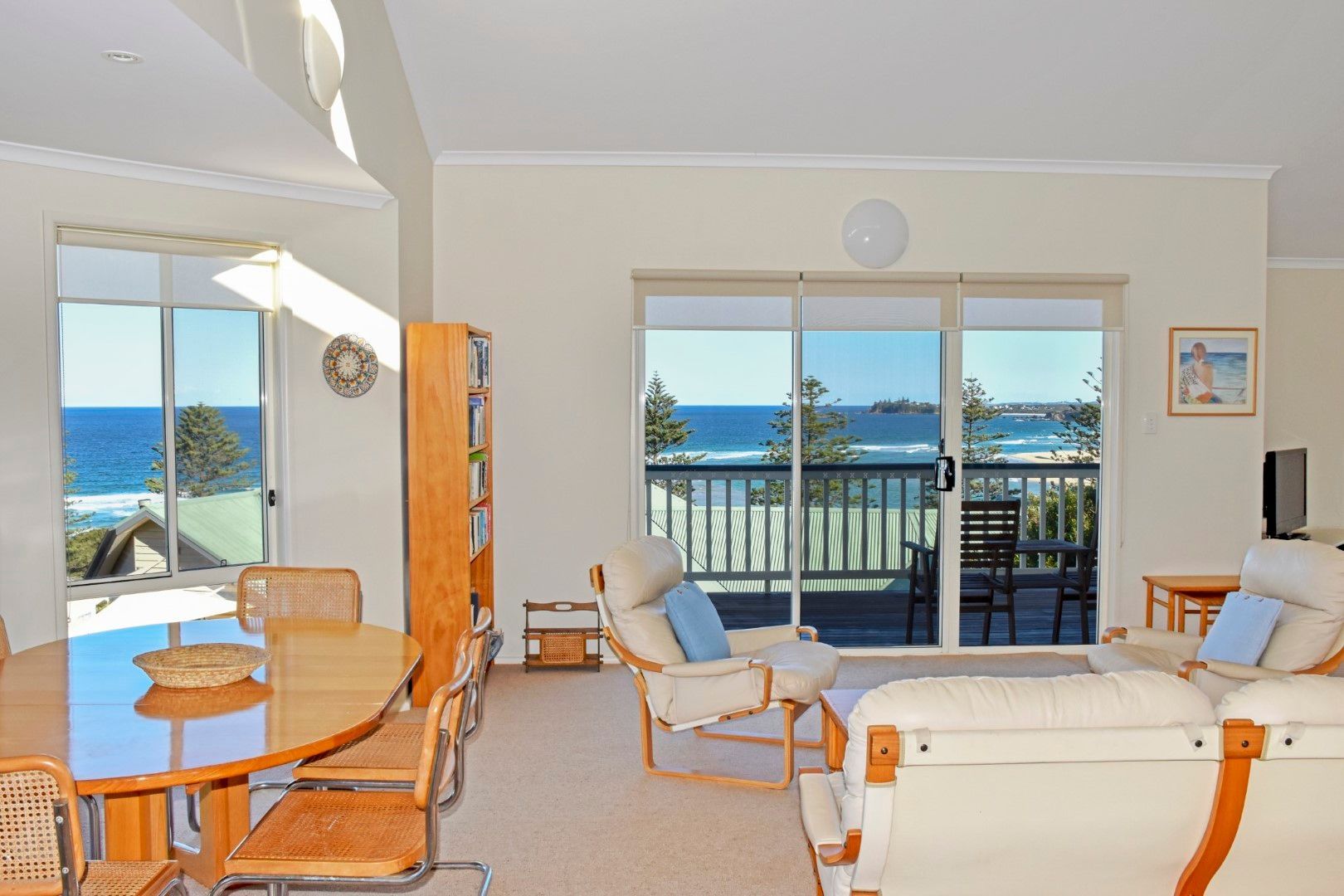 Bright beachside living room with glass doors, wicker furniture, and ocean view