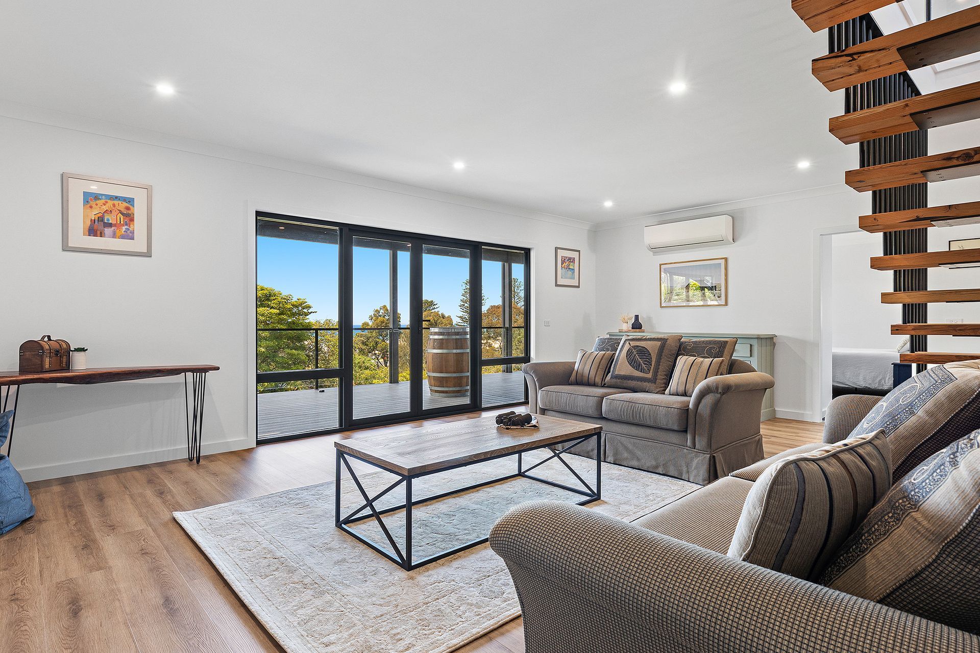 Bright modern living room with gray sofas, a rug, coffee table, and sliding glass doors to a balcony