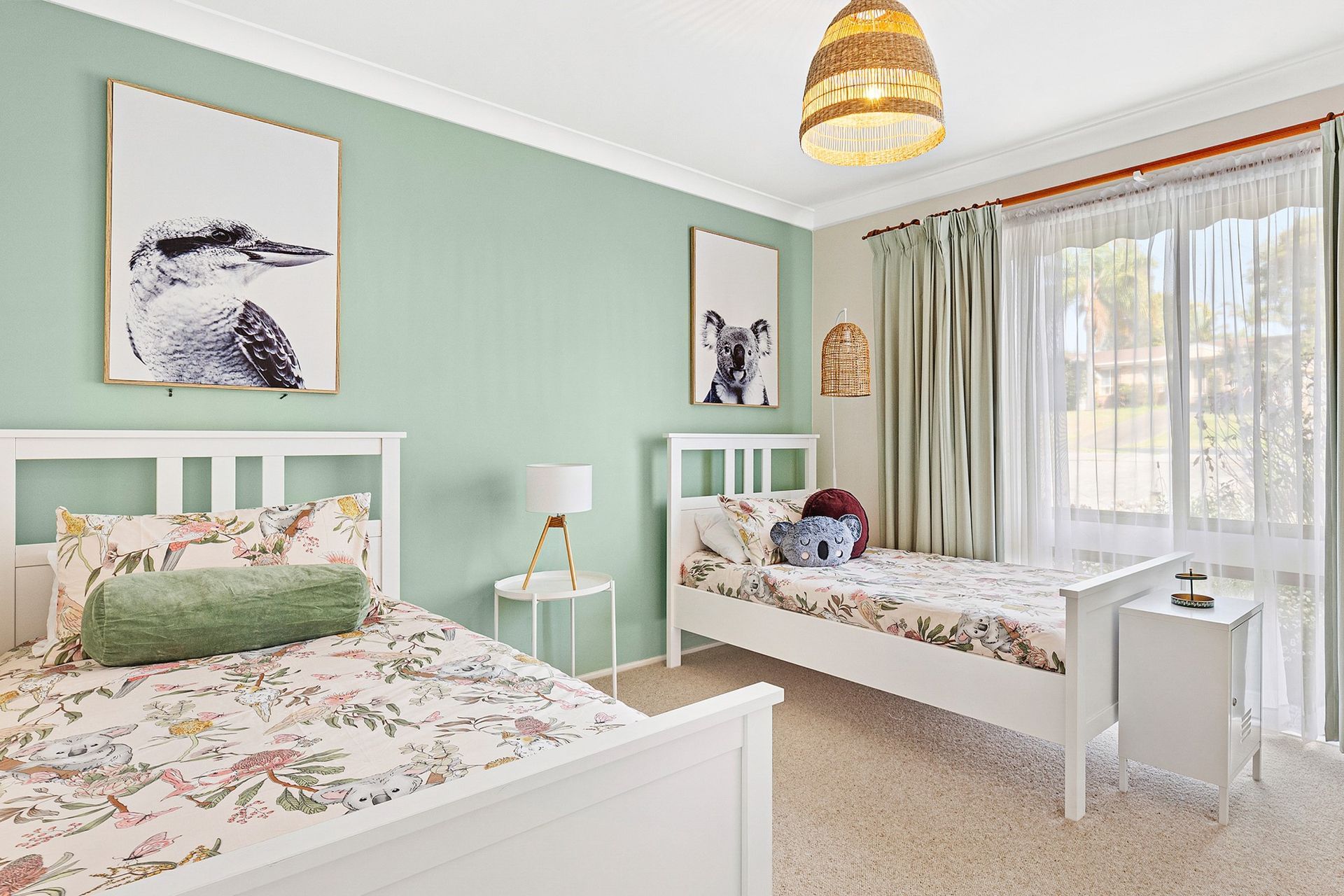 Bright pastel bedroom with white twin beds, floral bedding, and a window seat by large windows