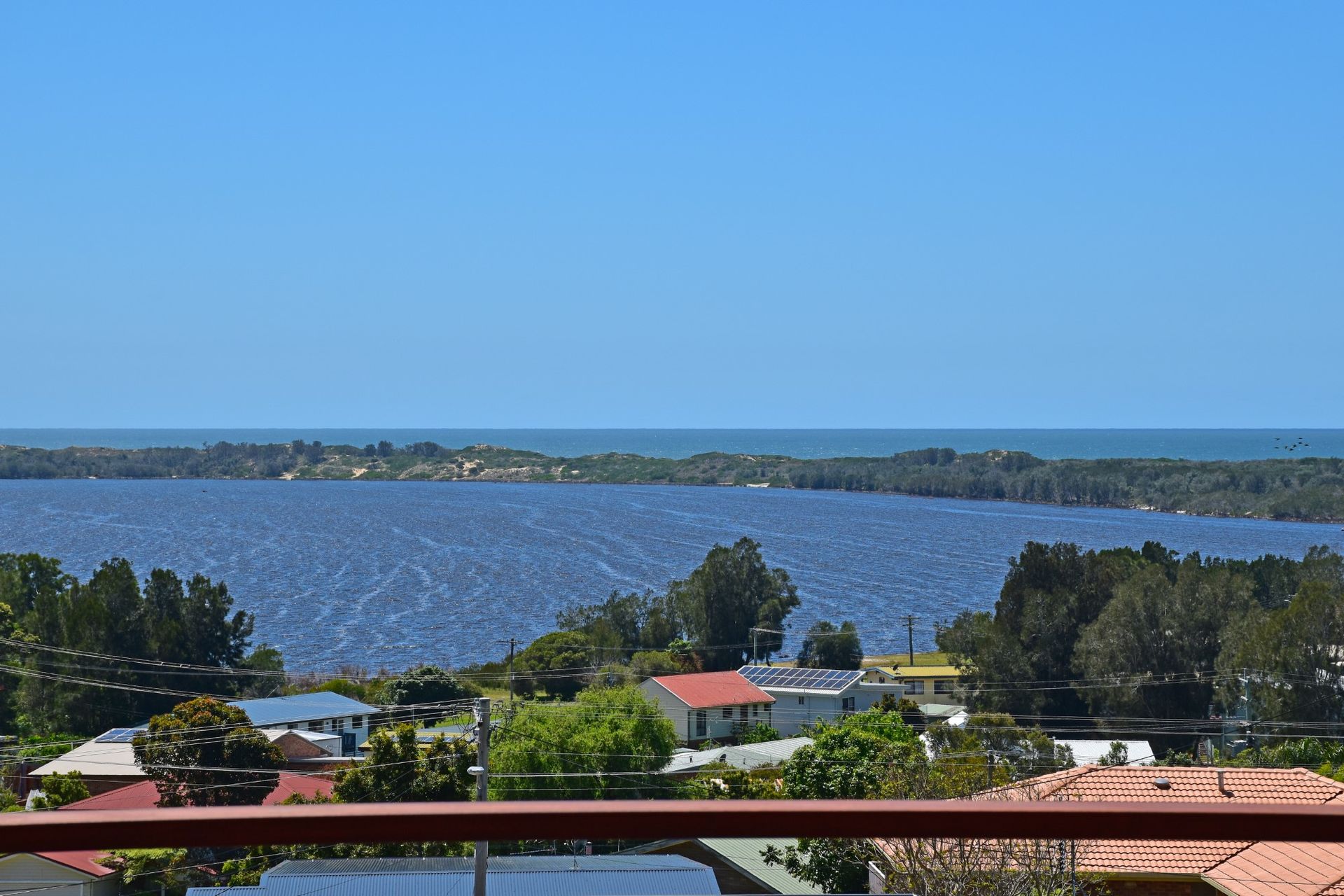 View of a large body of water, blue sky and trees.