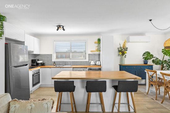 Whale Watcher @ Tuross Head - Bright kitchen with white cabinets, stainless fridge, wood island, and blue dining nook.
