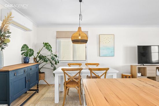 Whale Watcher @ Tuross Head - Bright dining room with white walls, table, wicker chairs, blue sideboard, plants, and TV 