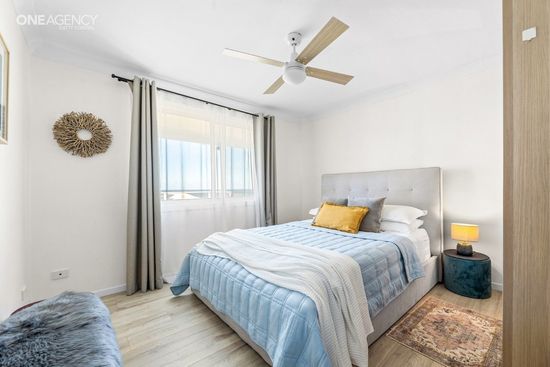Whale Watcher @ Tuross Head - Bright bedroom with a bed, blue bedding, , ceiling fan, and a small bedside table with a lamp.