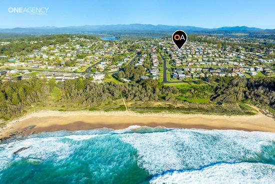 Whale Watcher @ Tuross Head - Aerial view of a coastal town with a sandy beach, surf, and homes beyond the shoreline