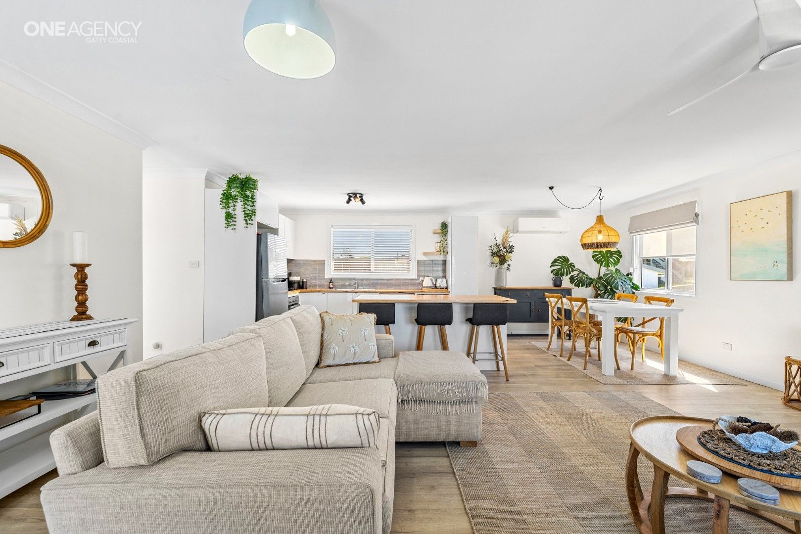 Whale Watcher @ Tuross Head - Bright open living-dining room with beige sectional sofa, and kitchen in the background
