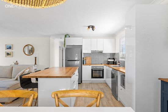 Whale Watcher @ Tuross Head - Bright modern kitchen and dining area with white cabinets, wooden island.