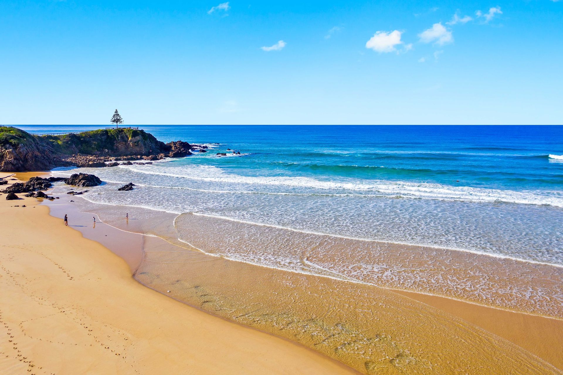 Sandy Tuross Head beach with surf and a rocky headland