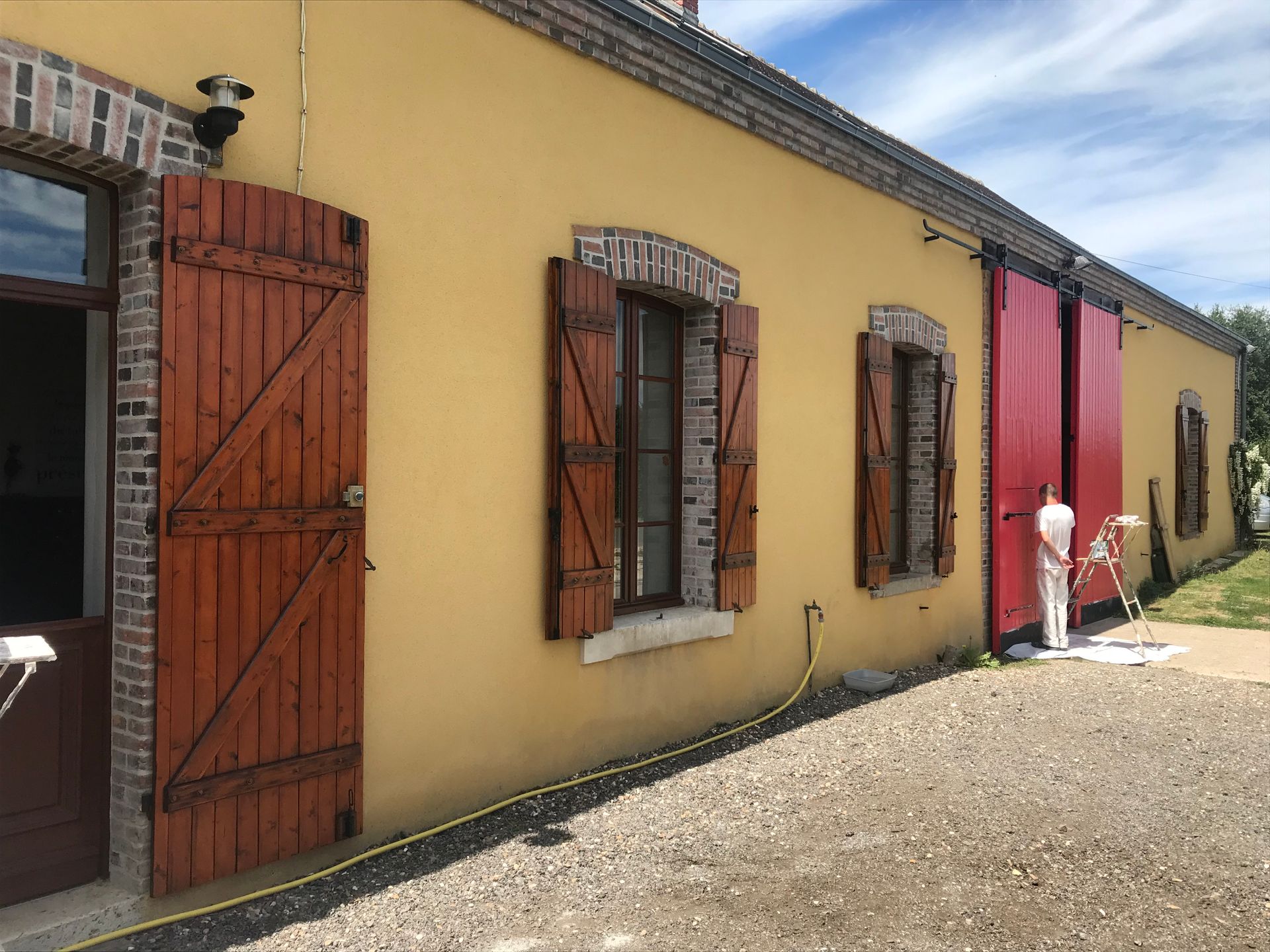 Photo d'une maison jaune avec des volets en bois