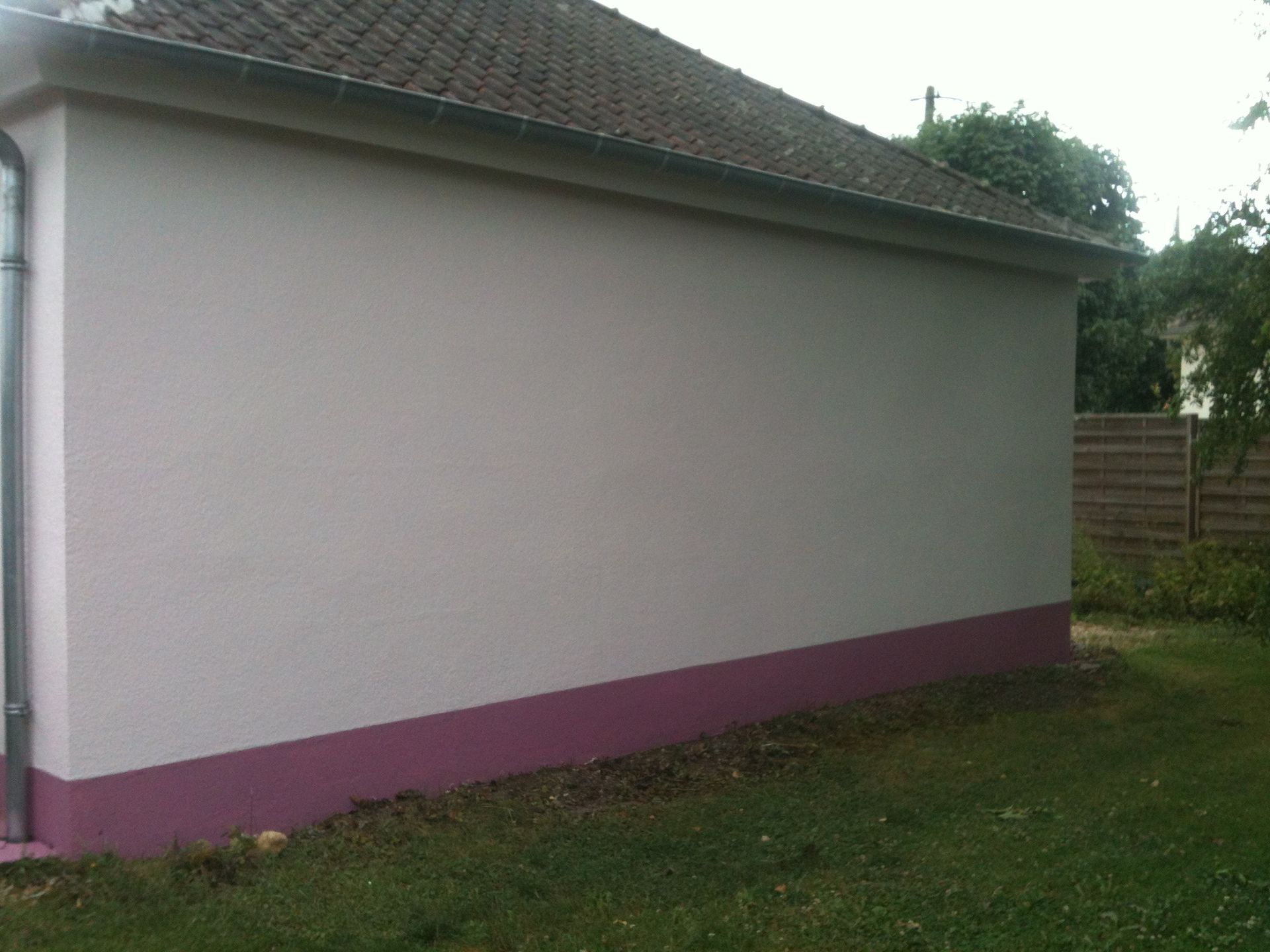 Photo du côté d'une maison avec un crépi blanc et rose