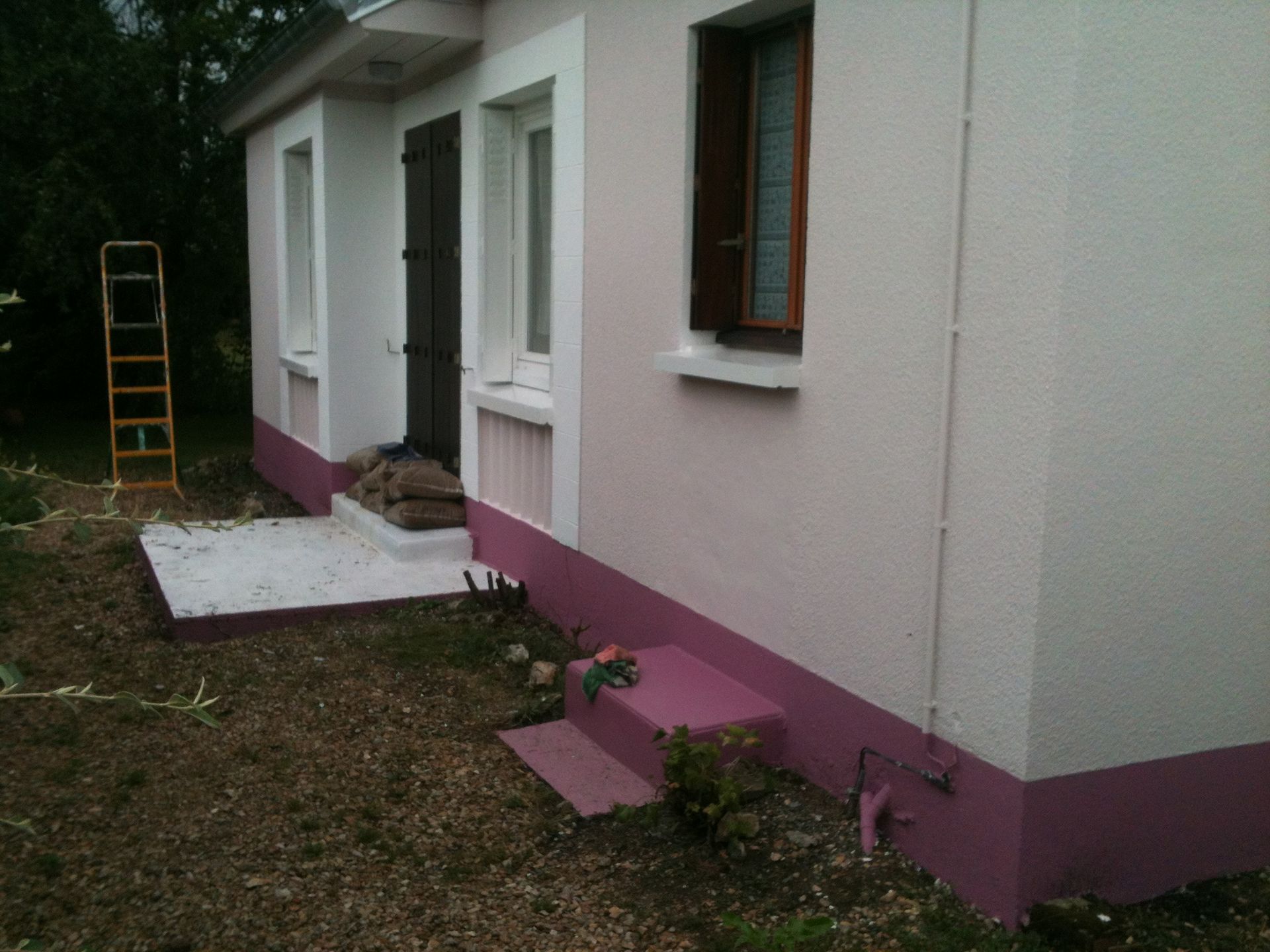 Photo de l'avant d'une maison blanche et une bande rose en bas