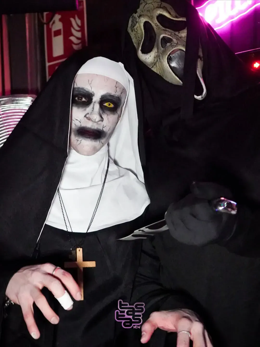 Una persona con un disfraz de monja y maquillaje aterrador posa con una máscara de Scream.