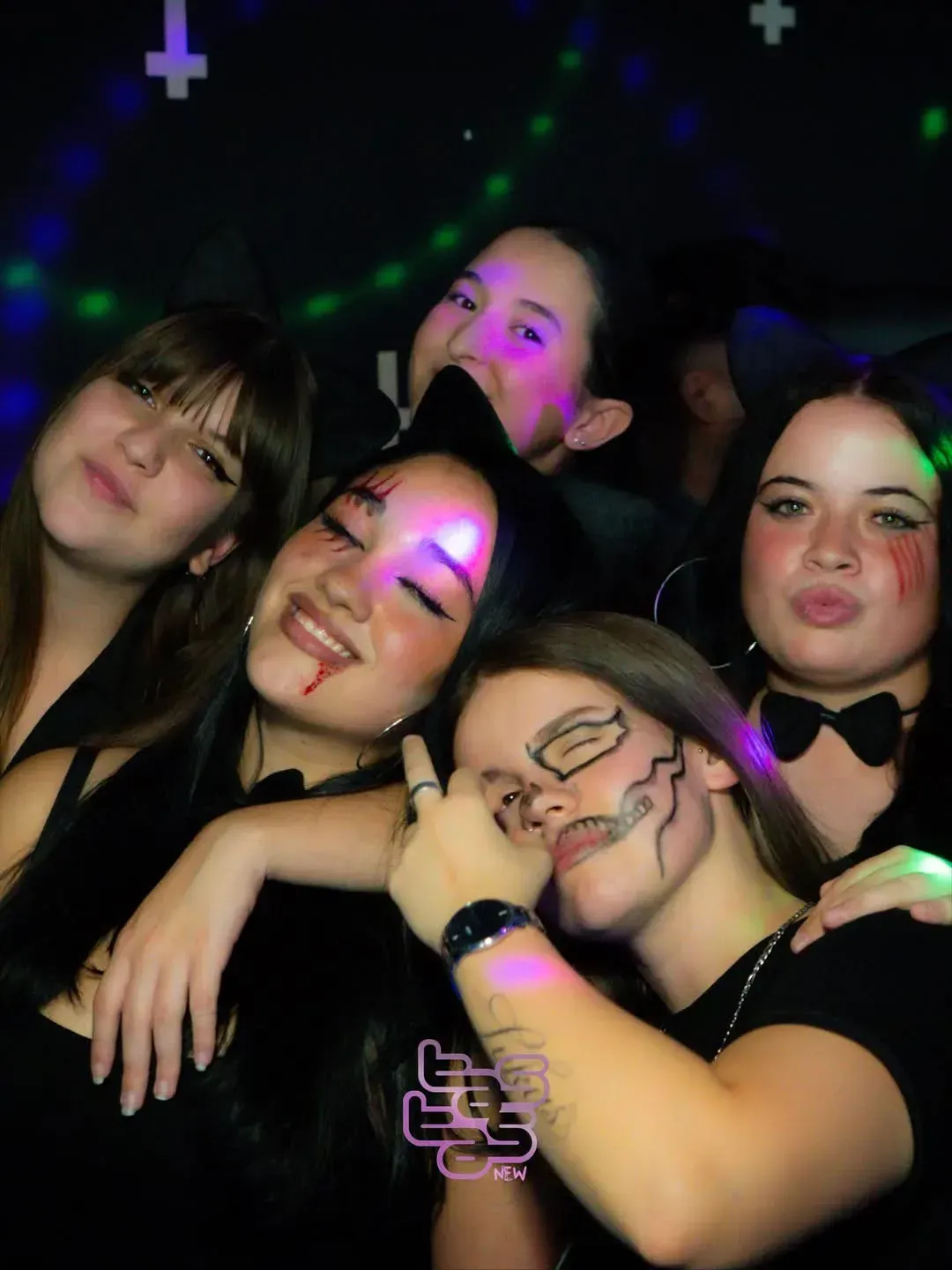 Grupo de amigos disfrazados de Halloween, en un ambiente oscuro. Algunos llevan sangre falsa, caras pintadas y pajaritas.