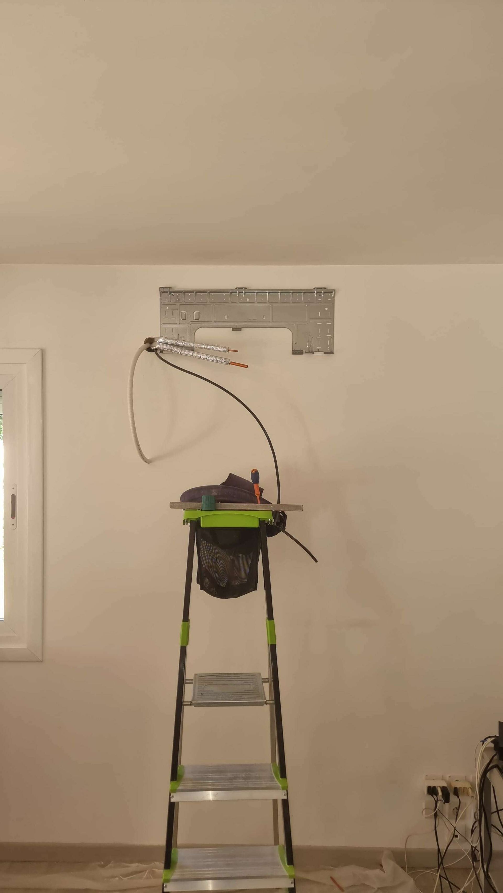 Installation d'une climatisation sur un mur blanc.