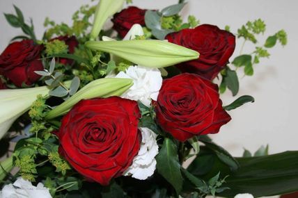 Frau steckt an einem Tisch voller Blumen ein Gesteck zusammen