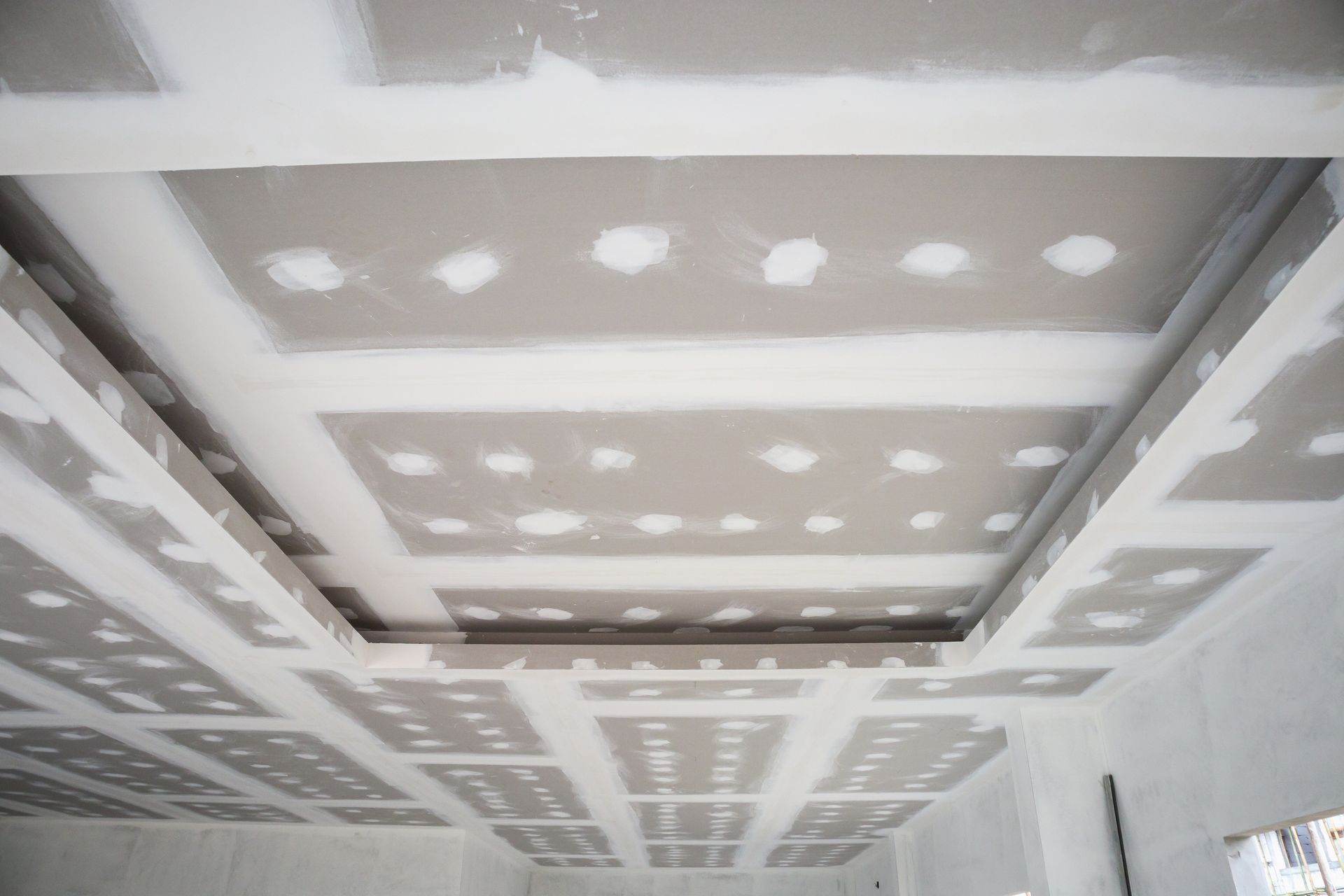 Plafond intérieur avec joints et raccords de plaques de plâtre, montrant des panneaux encastrés en construction