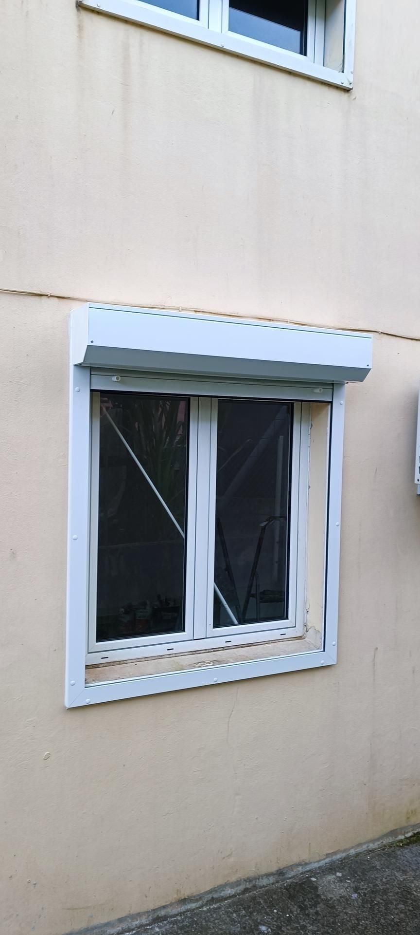 Fenêtre à cadre blanc avec un auvent vert sur un extérieur de bâtiment beige