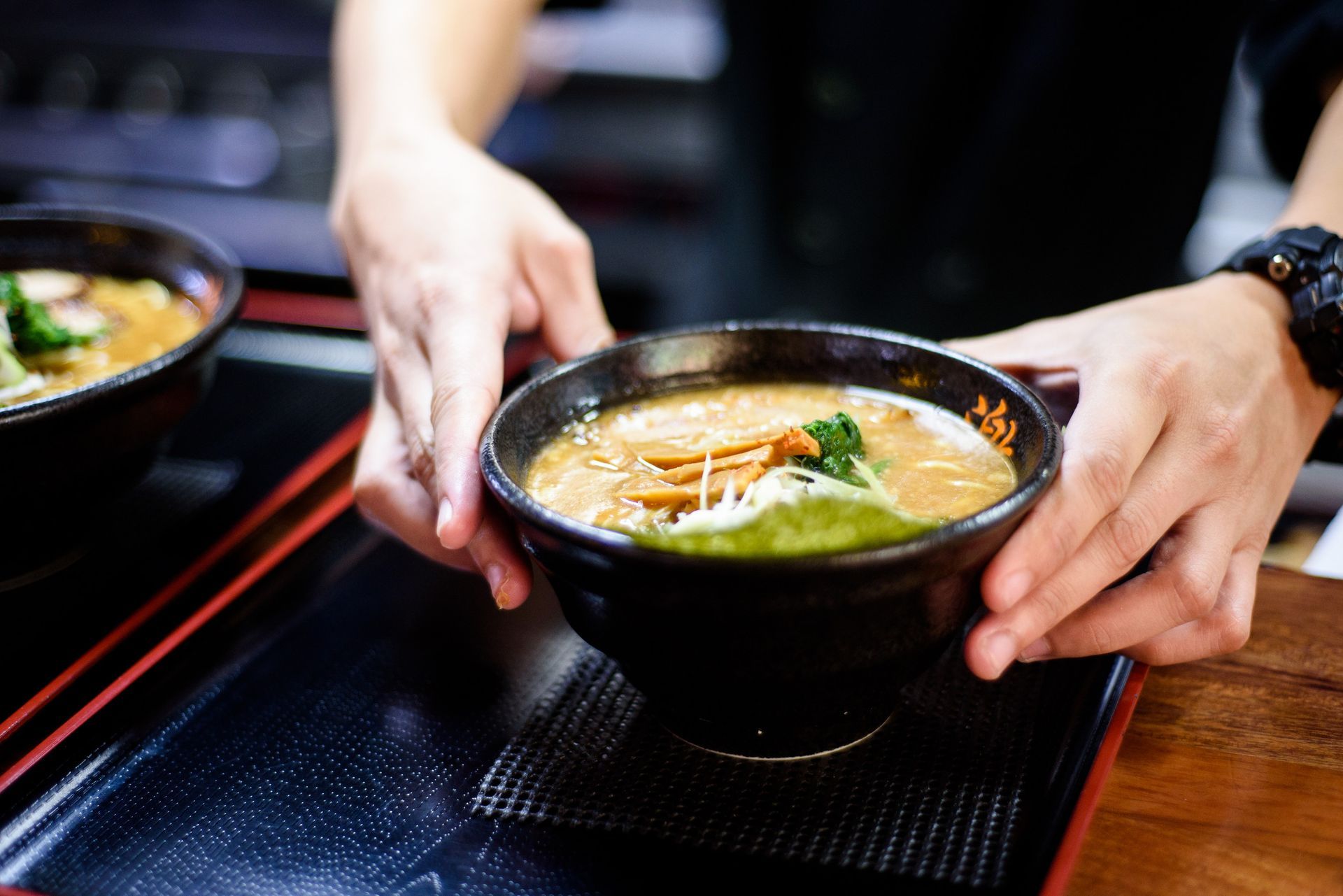 Una persona sostiene un tazón de sopa sobre una mesa.