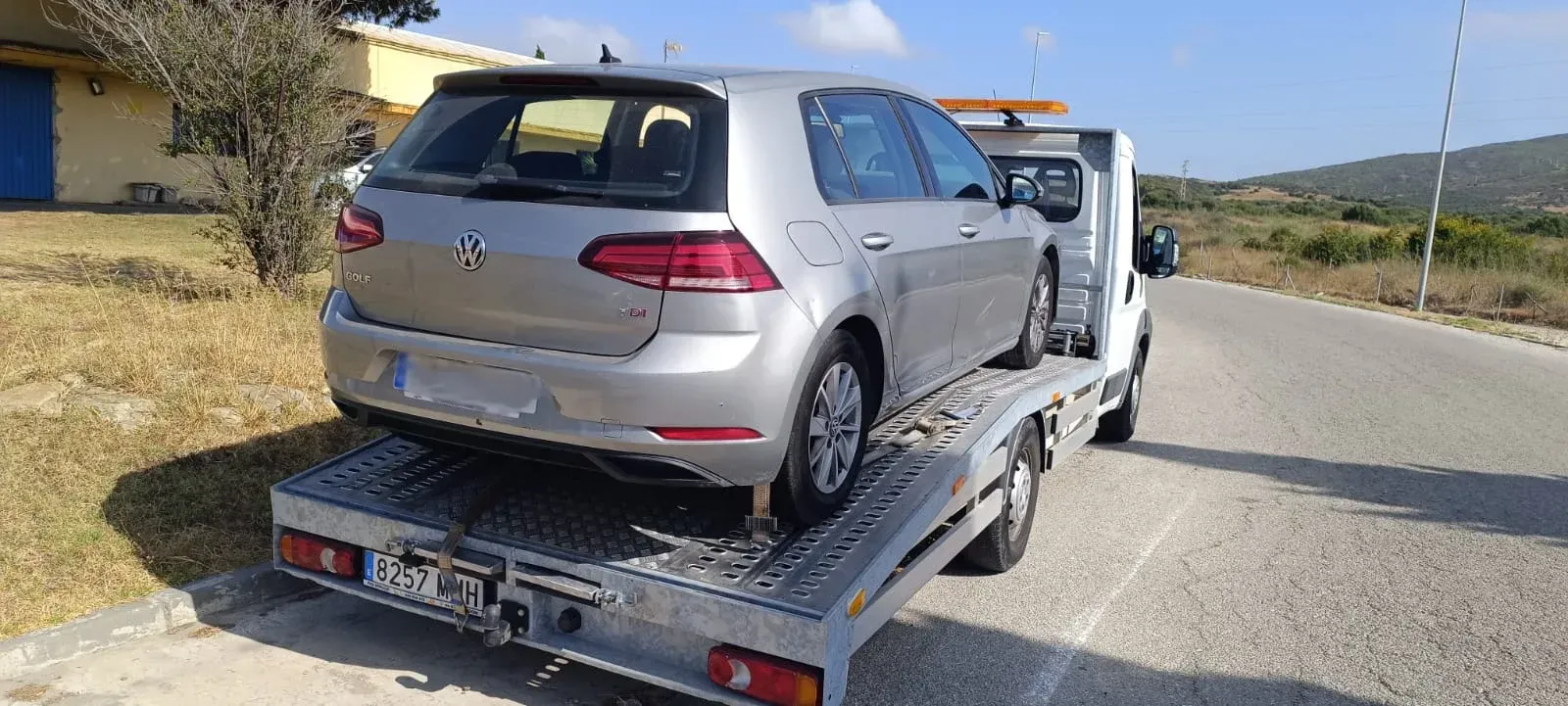 Un coche plateado está siendo remolcado por una grúa.