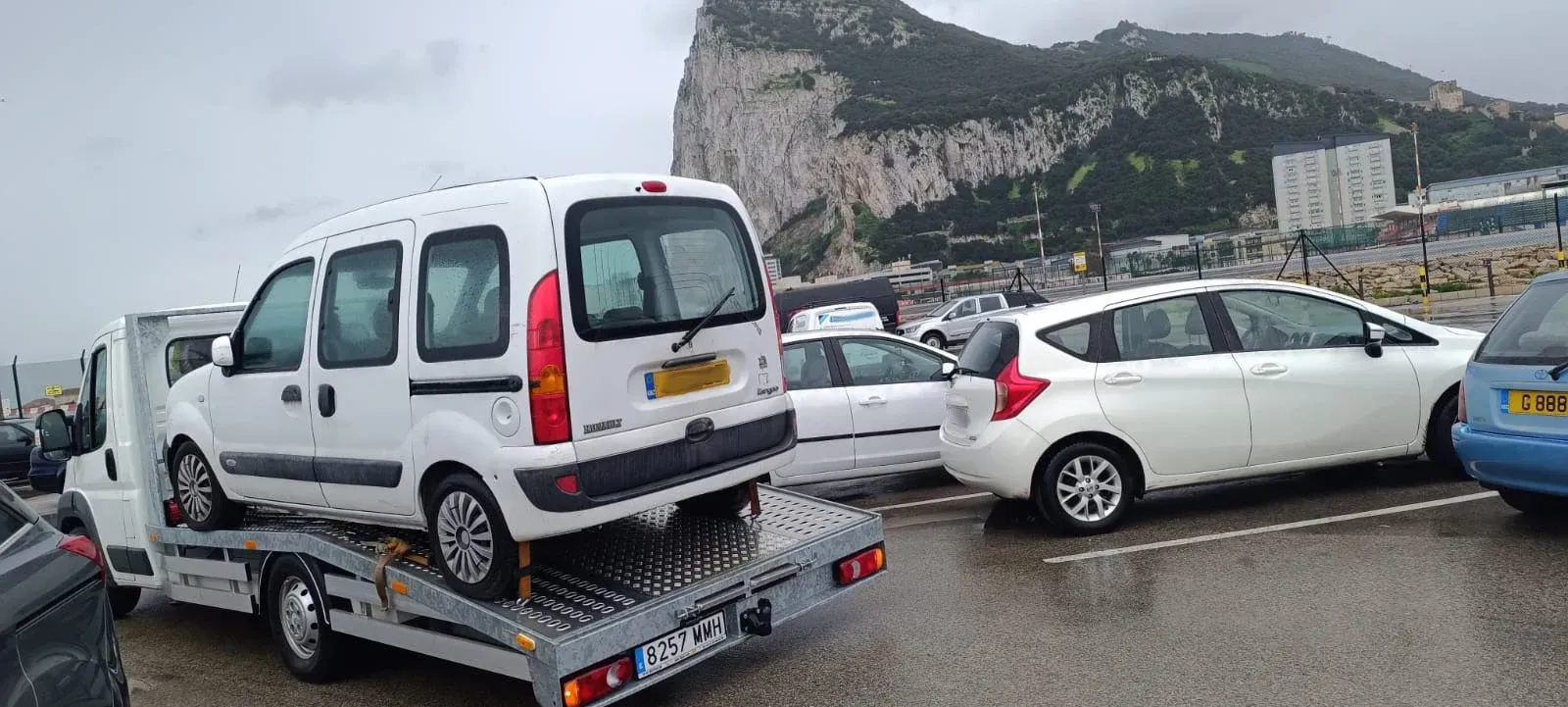 Una camioneta blanca está siendo remolcada por una grúa en un estacionamiento.