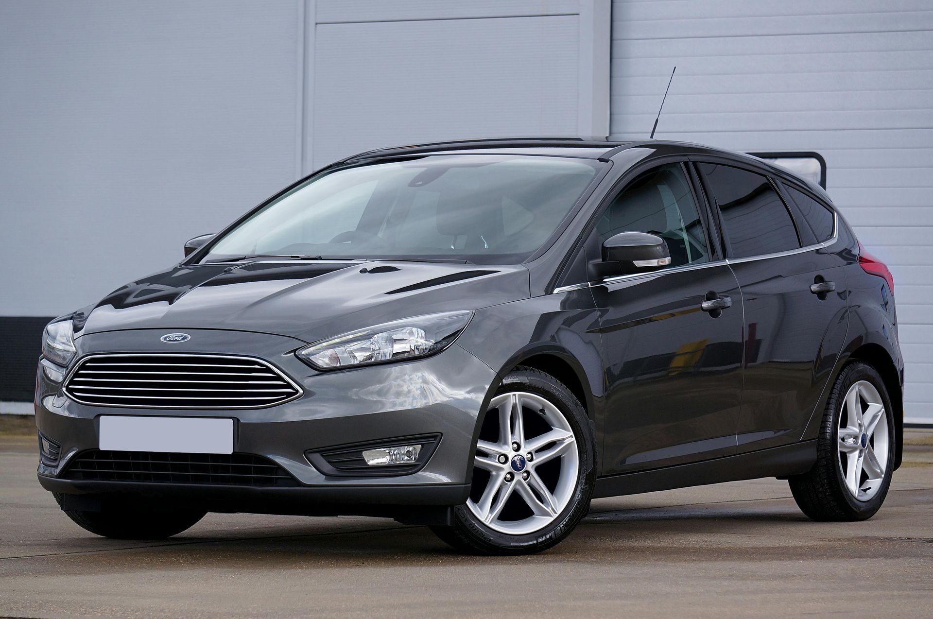 Un Ford Focus hatchback gris está estacionado frente a la puerta de un garaje.