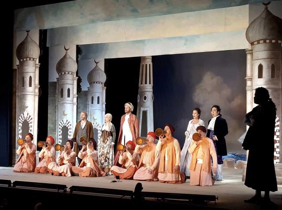 Eine Gruppe von Menschen auf einer Bühne mit einem Schloss im Hintergrund