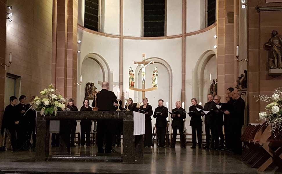 Eine Gruppe singender Menschen in einer Kirche mit einem Kreuz im Hintergrund