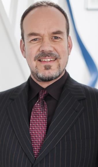 Ein Mann in Anzug und Krawatte lächelt in die Kamera