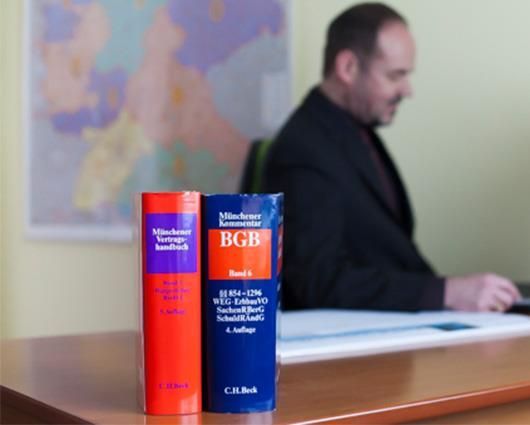 Ein Mann sitzt an einem Schreibtisch mit zwei Büchern, von denen eines den Titel BGB trägt
