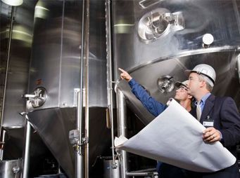 Dos hombres miran un plano en una fábrica.