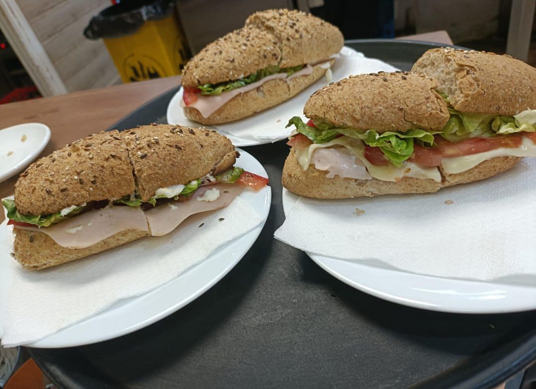 Hay tres sándwiches en platos en una bandeja sobre una mesa.