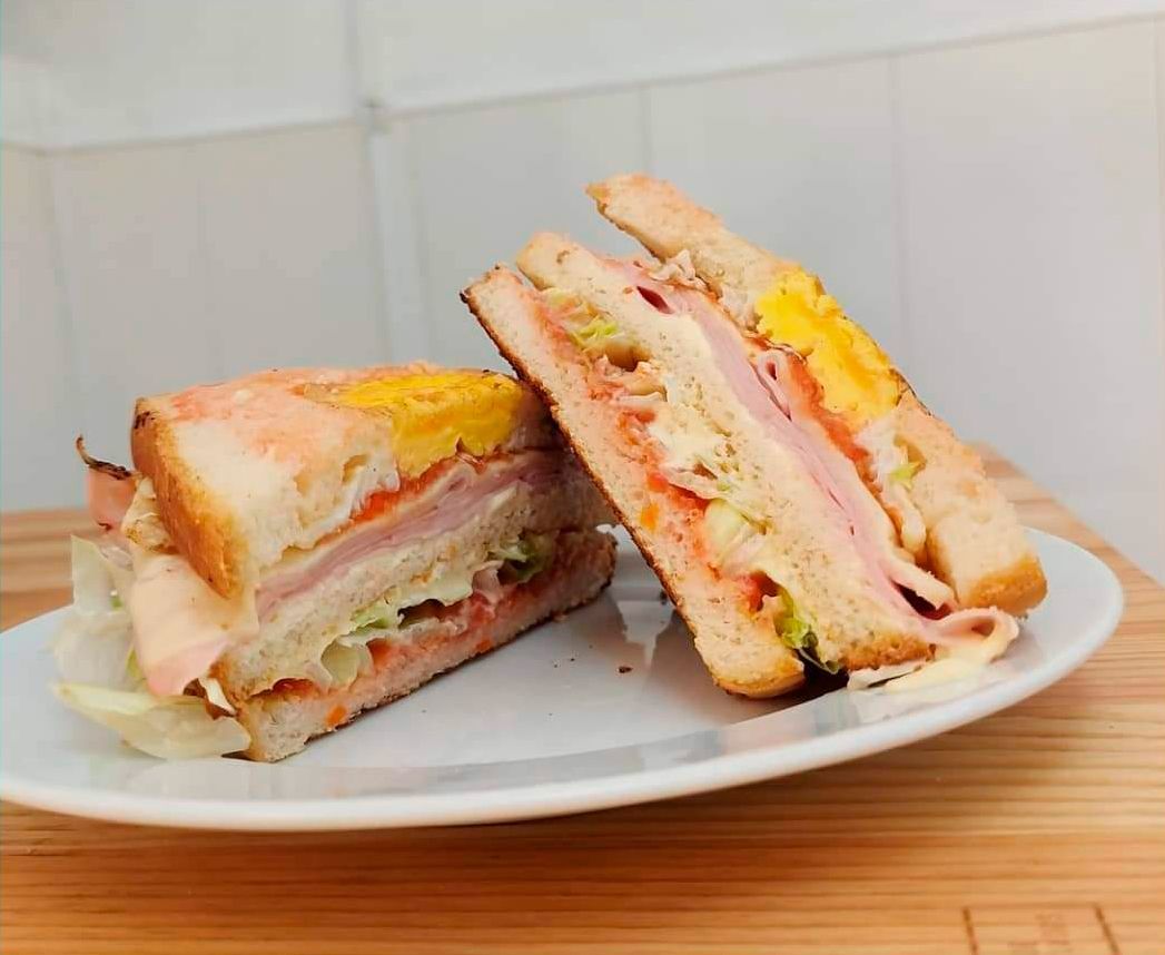 Un sándwich club se corta por la mitad en un plato blanco.