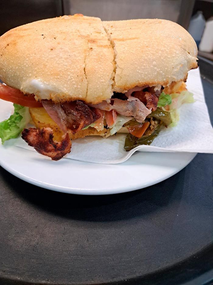 Un sándwich está en un plato blanco con una servilleta y un tenedor.