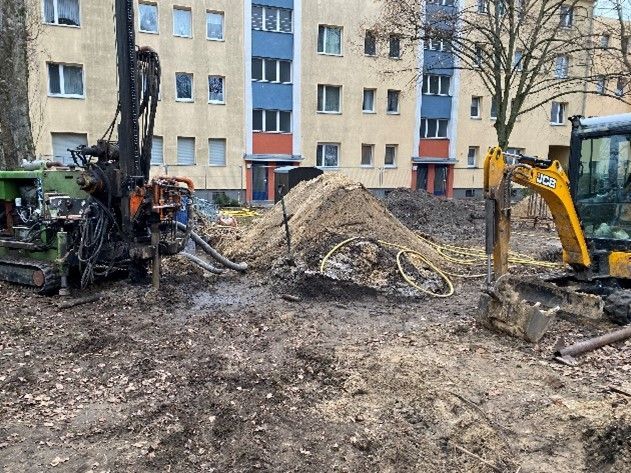 Eine Baustelle mit einem Erdhaufen und einem Gebäude im Hintergrund.