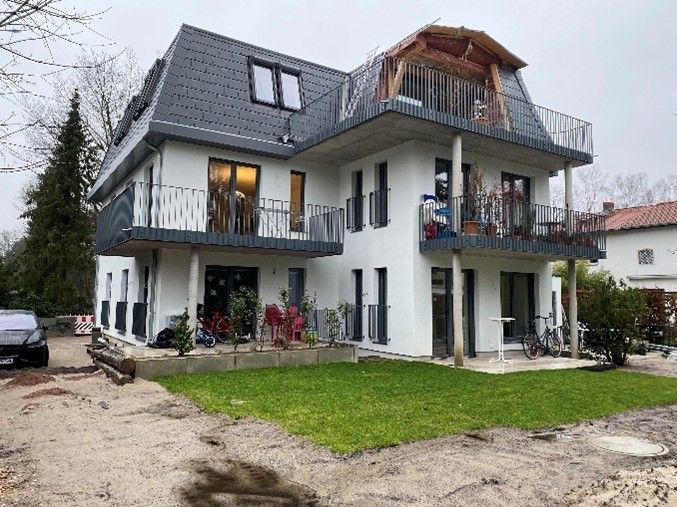 Ein großes weißes Haus mit Balkonen und einem davor geparkten Auto.