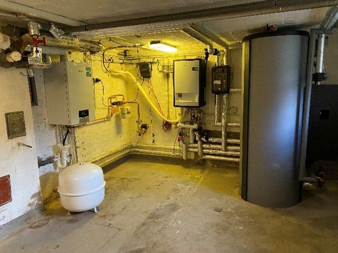 Ein Raum mit vielen Rohren und einer Heizung darin.