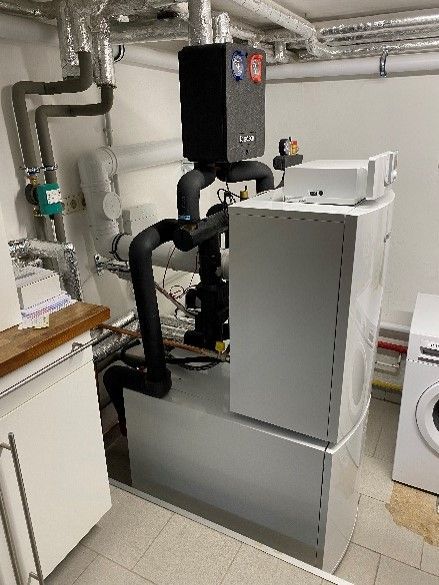 In einem Raum neben einer Waschmaschine steht ein Boiler.