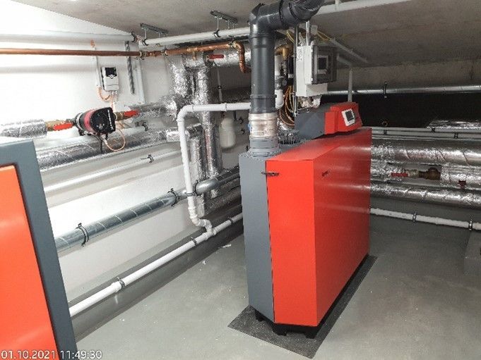 Ein roter Kessel steht in einem Raum mit Rohren