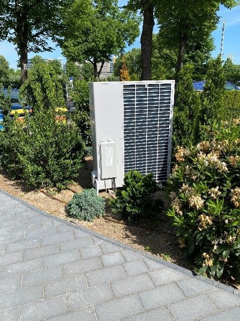 Eine weiße Klimaanlage steht mitten in einem Garten.