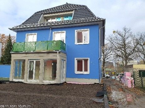 Ein blaues Haus mit grünem Balkon ist im Bau.
