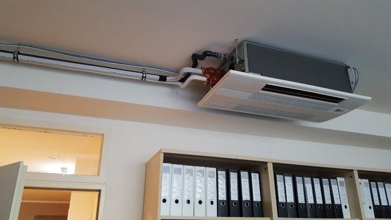 Ein Raum mit einer an der Decke montierten Klimaanlage und Ordnern auf Regalen.