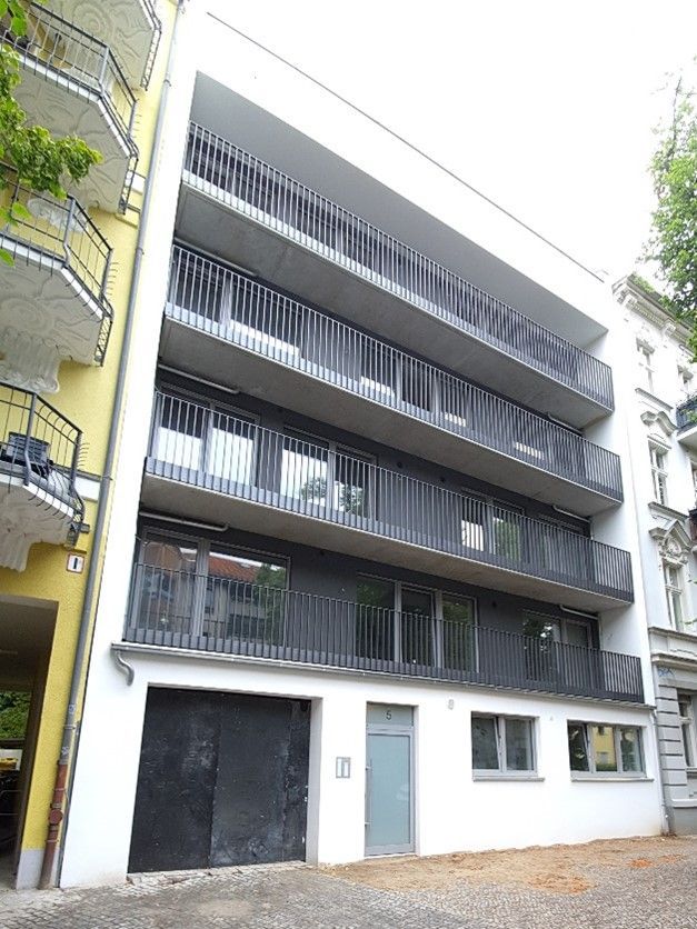 Ein großes weißes Gebäude mit vielen Balkonen und einer Garage.